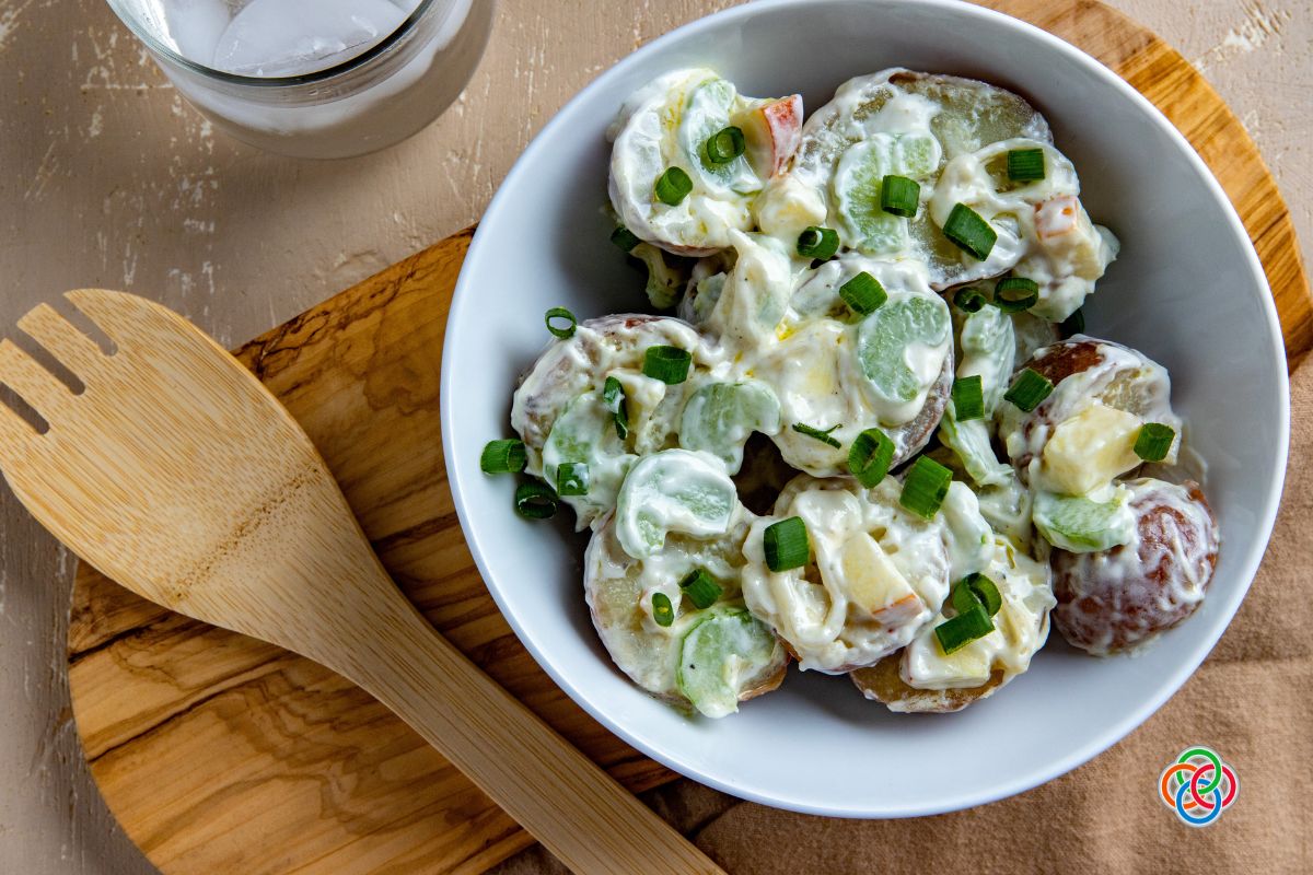 Apple celery potato salad in a bowl | Irish American Mom Bowl of potato salad on a board with a wooden fork