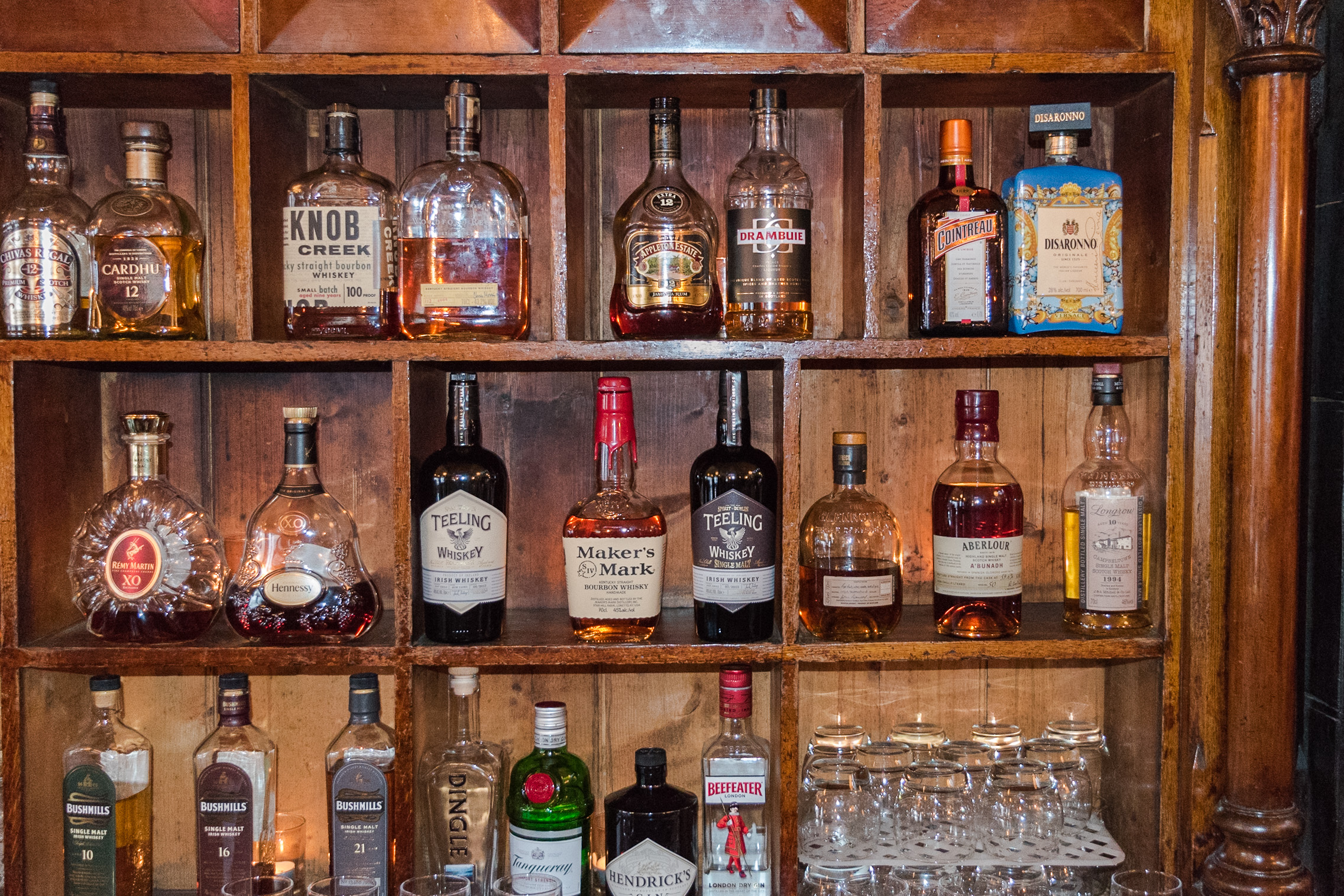 Whiskey bottles on a wooden shelf in a pub