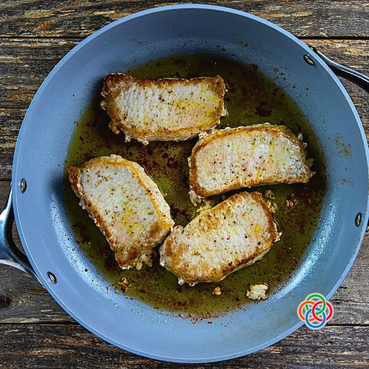 Golden pork chops frying in a skillet | Irish American Mom Cooking pork chops in oil in a skillet