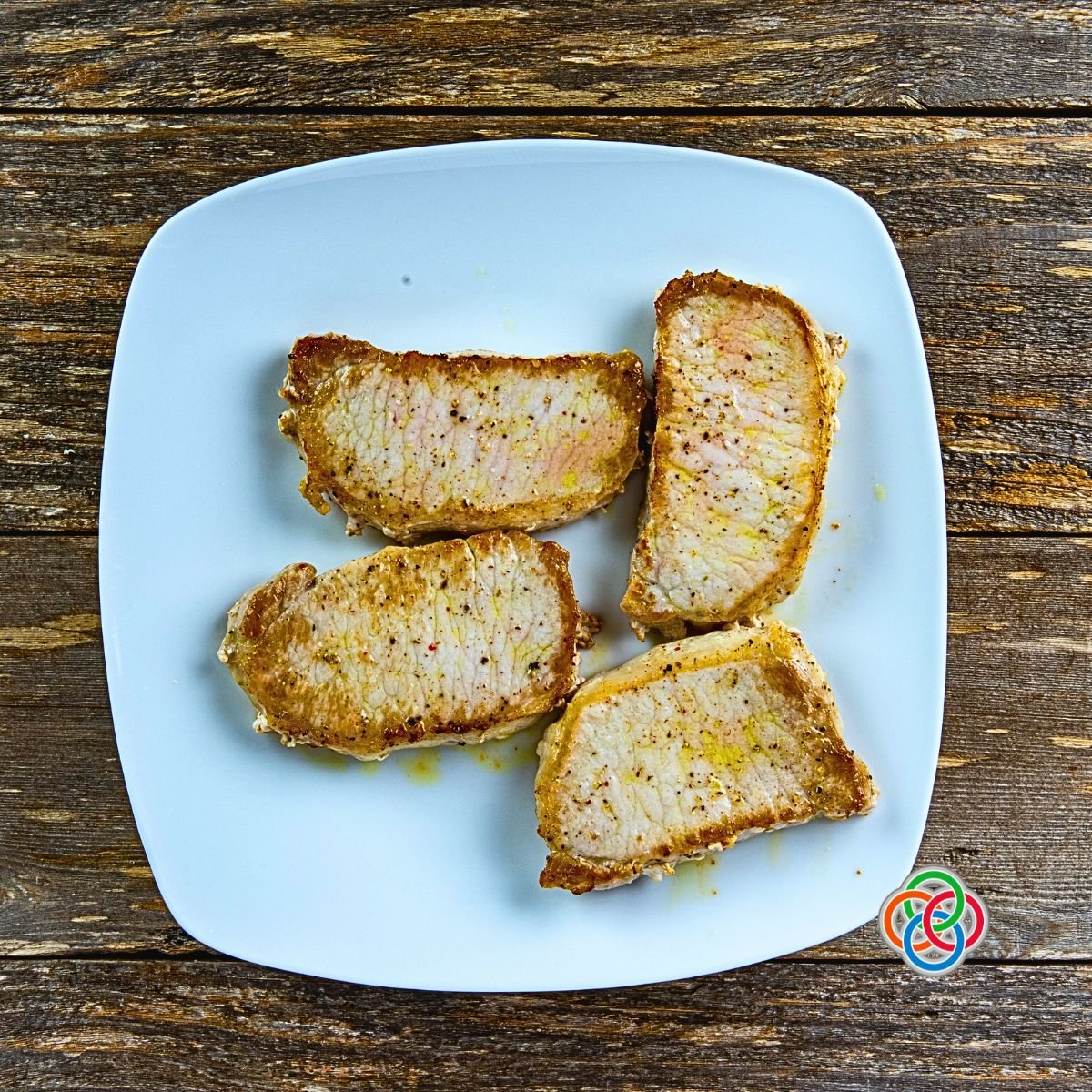 Resting pork chops after frying in a skillet | Irish American Mom Four fried pork chops on a platter