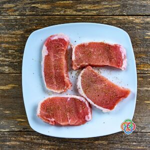 Seasoned raw pork chops on a platter