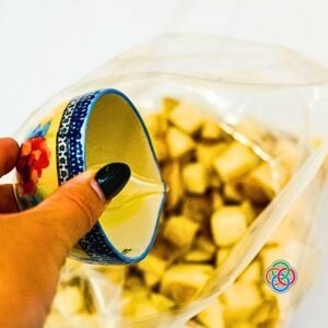 Pouring olive oil on a bag of chopped potatoes