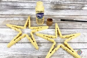 Wooden stars beside a paint brush and bottle of yellow paint
