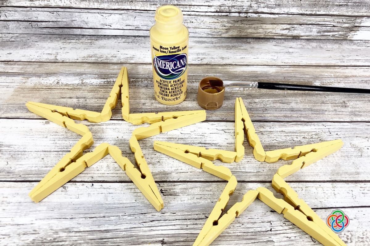 Wooden stars beside a paint brush and bottle of yellow paint