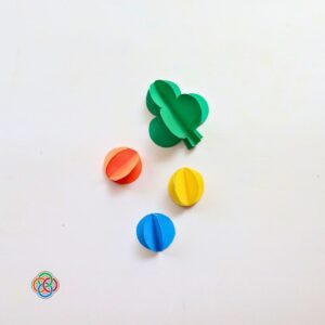 Completed 3D paper shamrock and colorful 3D paper balls made from folded circles for a Saint Patrick's Day garland craft, with Irish American Mom logo in the corner.