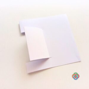 Cutting pop up piece for Pop Up Rainbow Card Craft | Irish American Mom White cardstock card with a cut and folded pop-up section prepared inside for a Saint Patrick's Day rainbow pop up card craft.