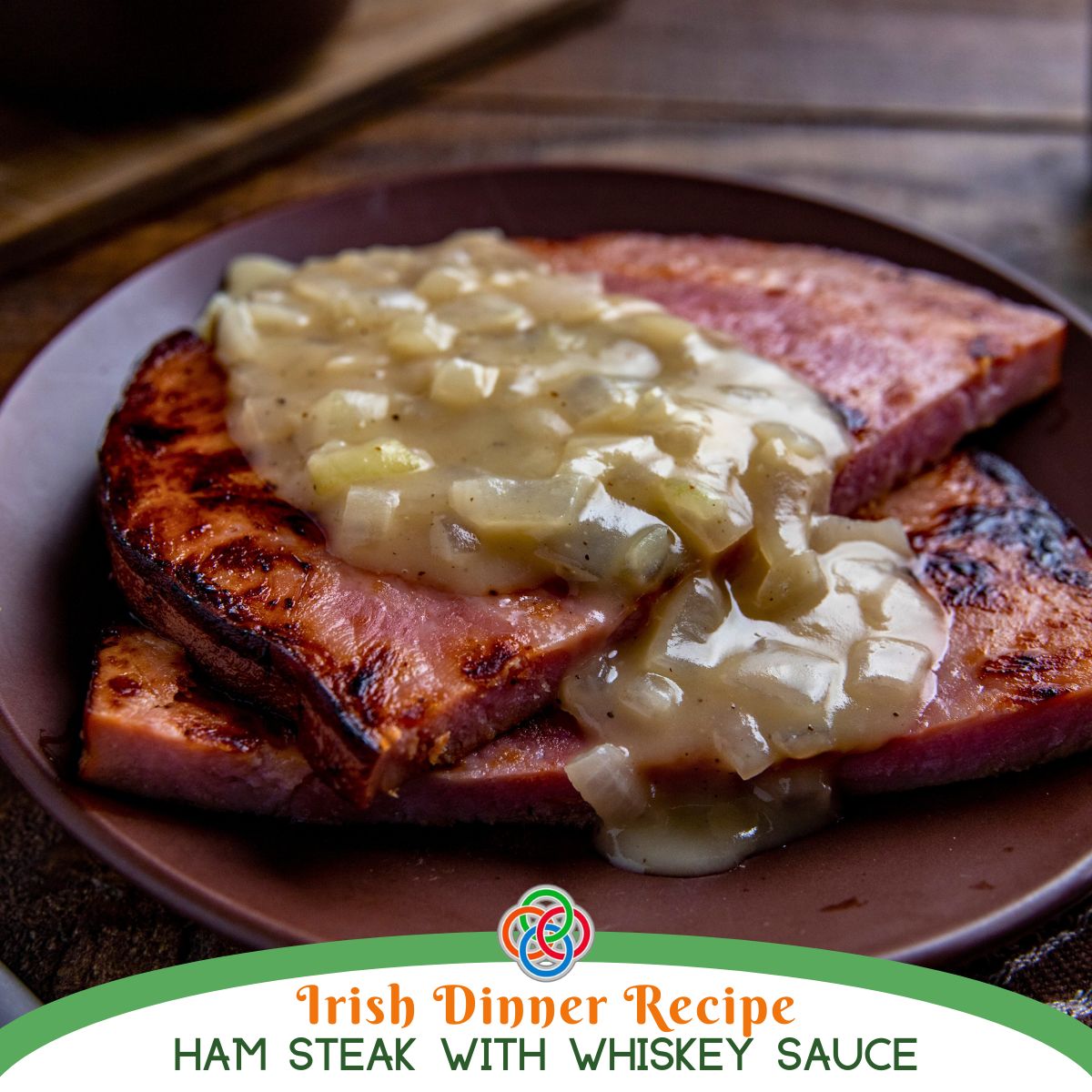 Ham steaks topped with creamy onion whiskey sauce on a brown plate, with text overlay reading “Irish Dinner Recipe Ham Steak with Whiskey Sauce.”