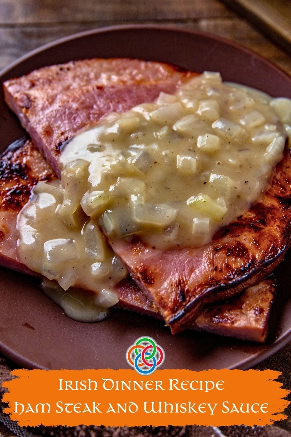 Ham steaks topped with creamy onion whiskey sauce on a brown plate, with text overlay reading “Irish Dinner Recipe Ham Steak and Whiskey Sauce.”