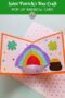 Pinterest graphic titled “Saint Patrick’s Day Craft Pop Up Rainbow Card” showing an open handmade card with a 3D rainbow, shamrocks, and a pot of gold on an orange-bordered background.