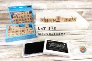 Stamping a message on book spines for a dec | Irish American Mom Alphabet stamps and black ink pad beside white painted books stamped with