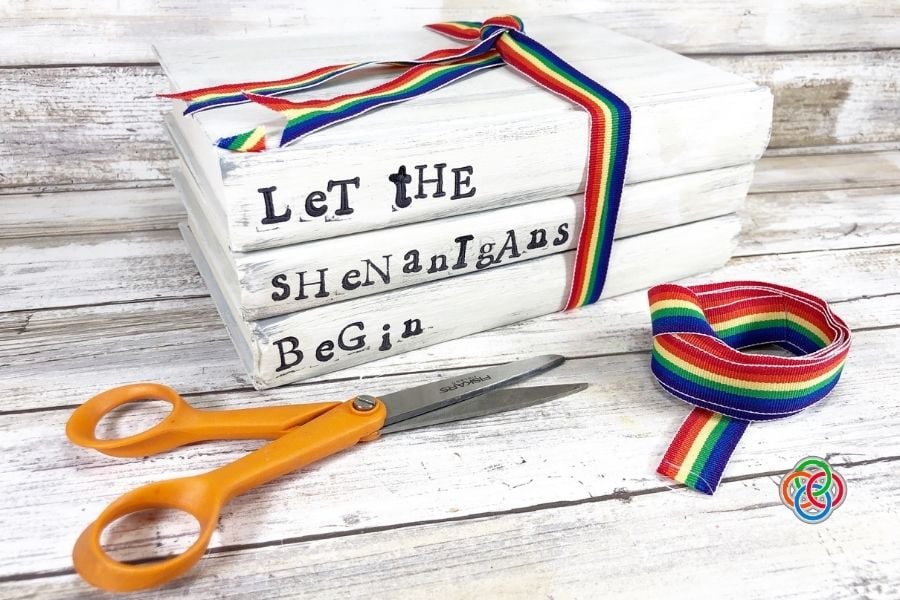 Tying ribbon around a decorative book stack | Irish American Mom Stack of white painted books stamped