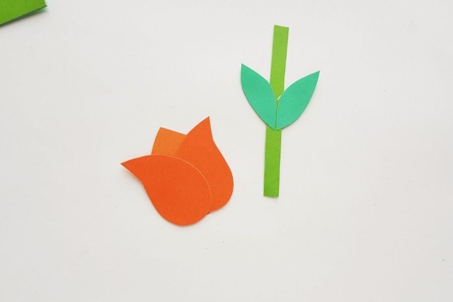 Paper pieces glued together to form an orange tulip, a stem and leaves.