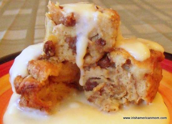 Bowl of cinnamon raisin bread pudding topped with creamy custard sauce.