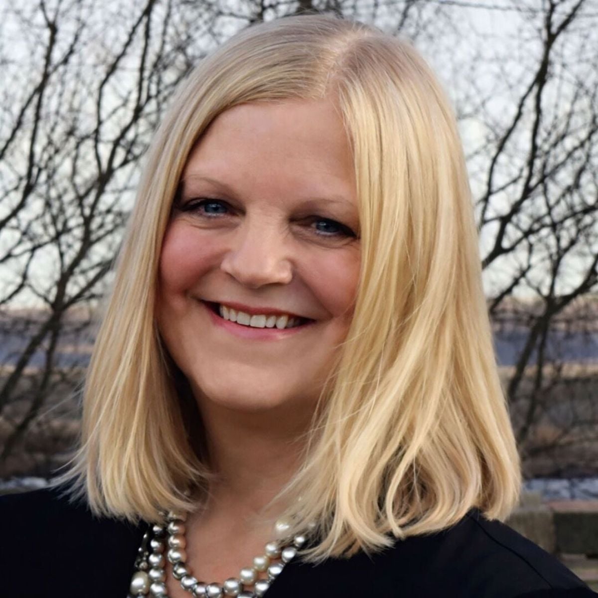Portrait of author Carrie Kabak, a blonde woman smiling outdoors, known for writing the novel Shibby Magee.