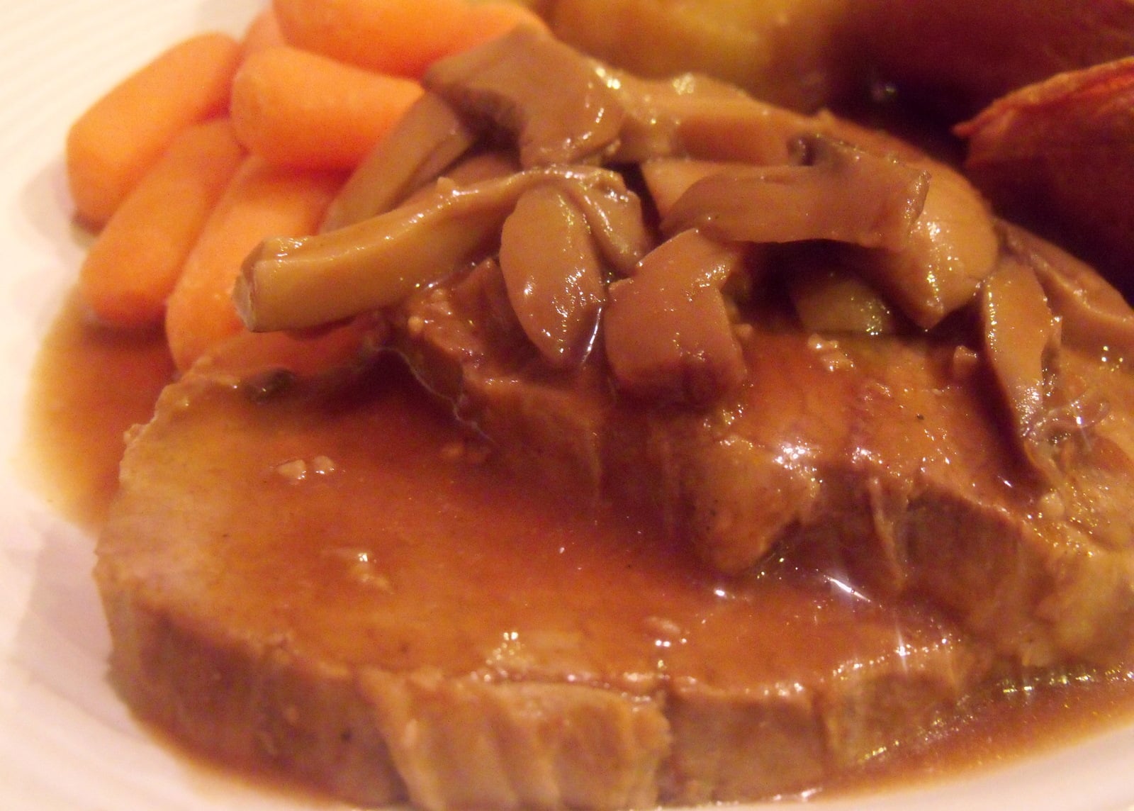 Tender crockpot roast beef in mushroom gravy served with vegetables.