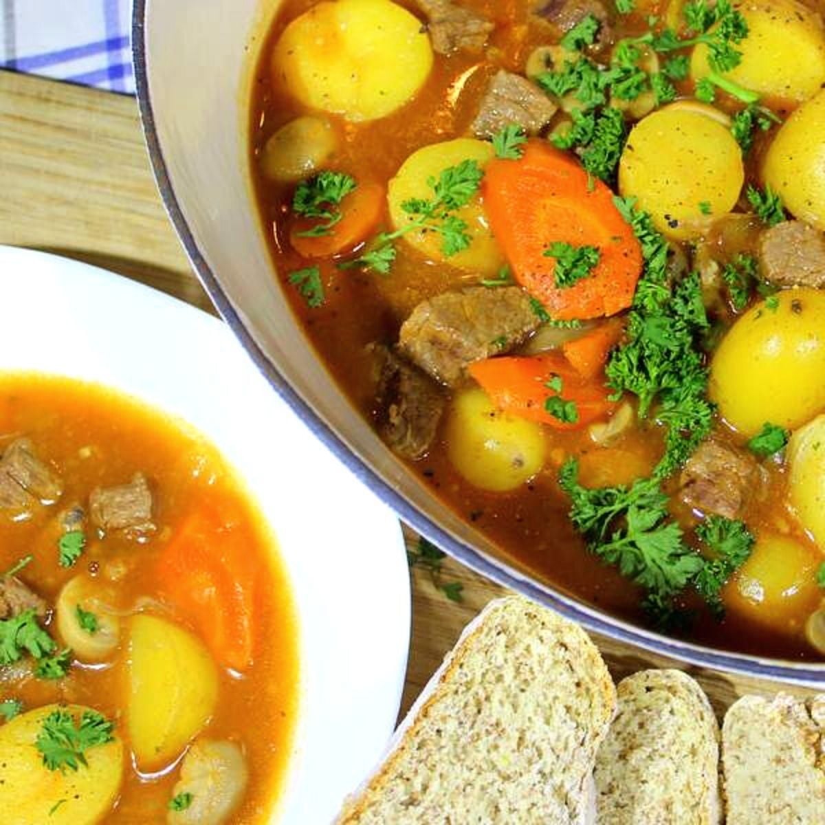 Pot of traditional Irish beef stew with carrots and potatoes served with brown bread.