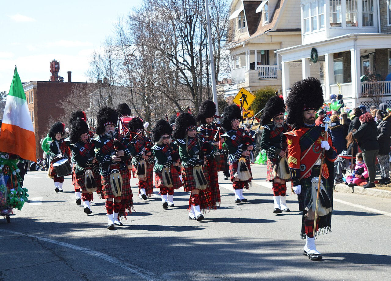 Pipe band with flags in a parade on a street with houses