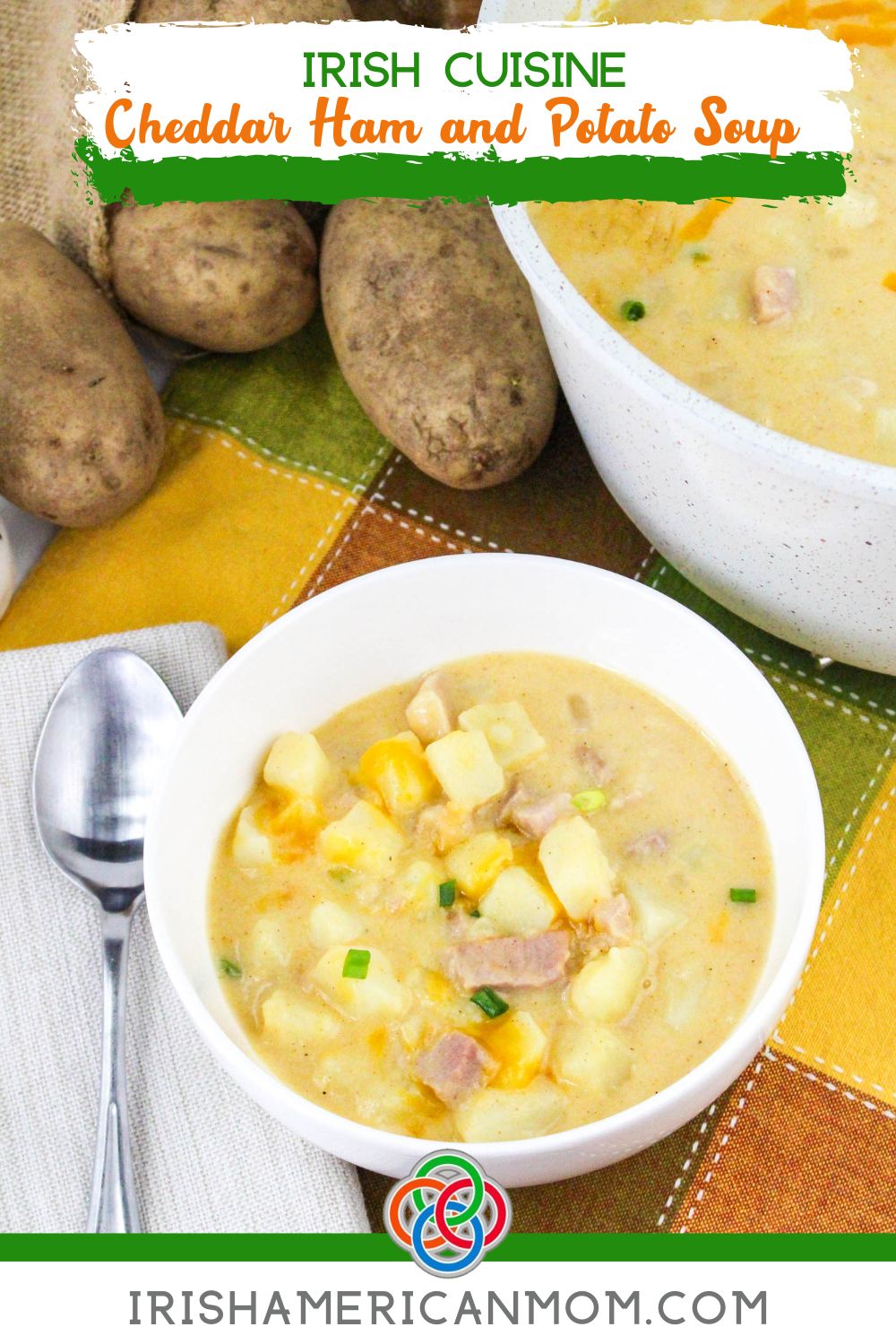 Bowl of creamy Irish cheddar ham and potato soup with chunks of potato and ham, styled with whole potatoes and a spoon, with text overlay reading Irish Cuisine Cheddar Ham and Potato Soup.