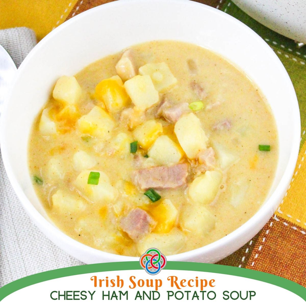Bowl of creamy cheddar ham and potato soup with chunks of potato, ham, melted cheese, and green onions, over a text banner.