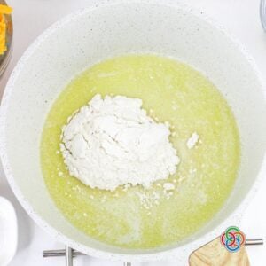 Flour added to melted butter in a pan to make a roux, the base for thickening a creamy ham and potato soup.