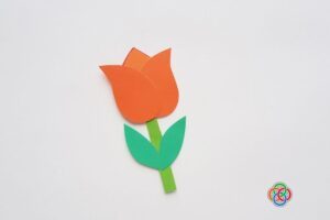 Completed paper tulip craft with orange petals, green stem, and leaves on a white background.