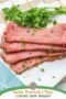 Slices of cooked corned beef brisket with a seasoned crust garnished with parsley on a white plate plust text banners.