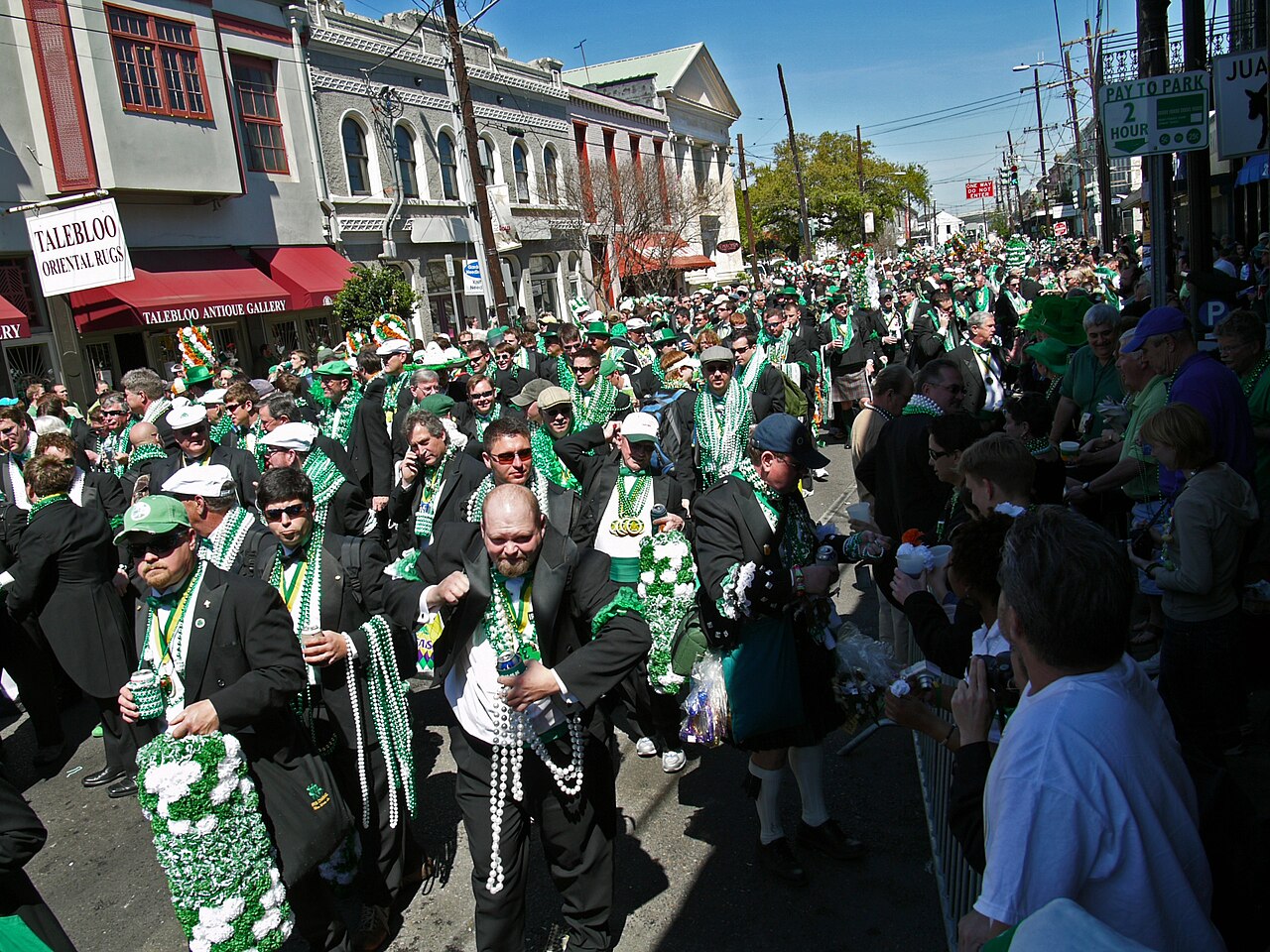 Parade of people wearing green and white in a city street in New Orleans