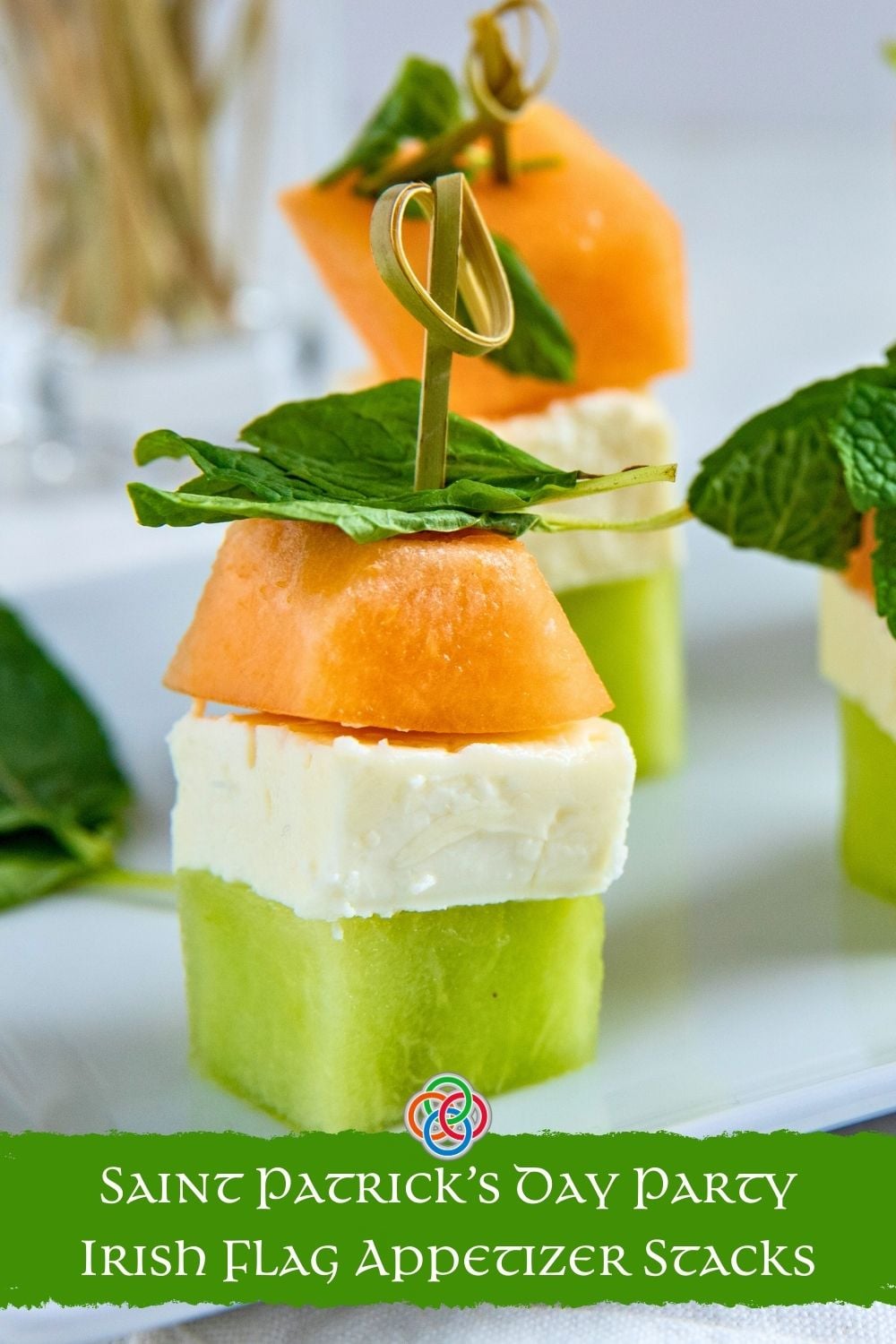 Close-up Pinterest graphic of an Irish flag appetizer stack made with honeydew, feta cheese, and cantaloupe topped with mint and a cocktail pick, with text reading “Saint Patrick’s Day Party Irish Flag Appetizer Stacks.”