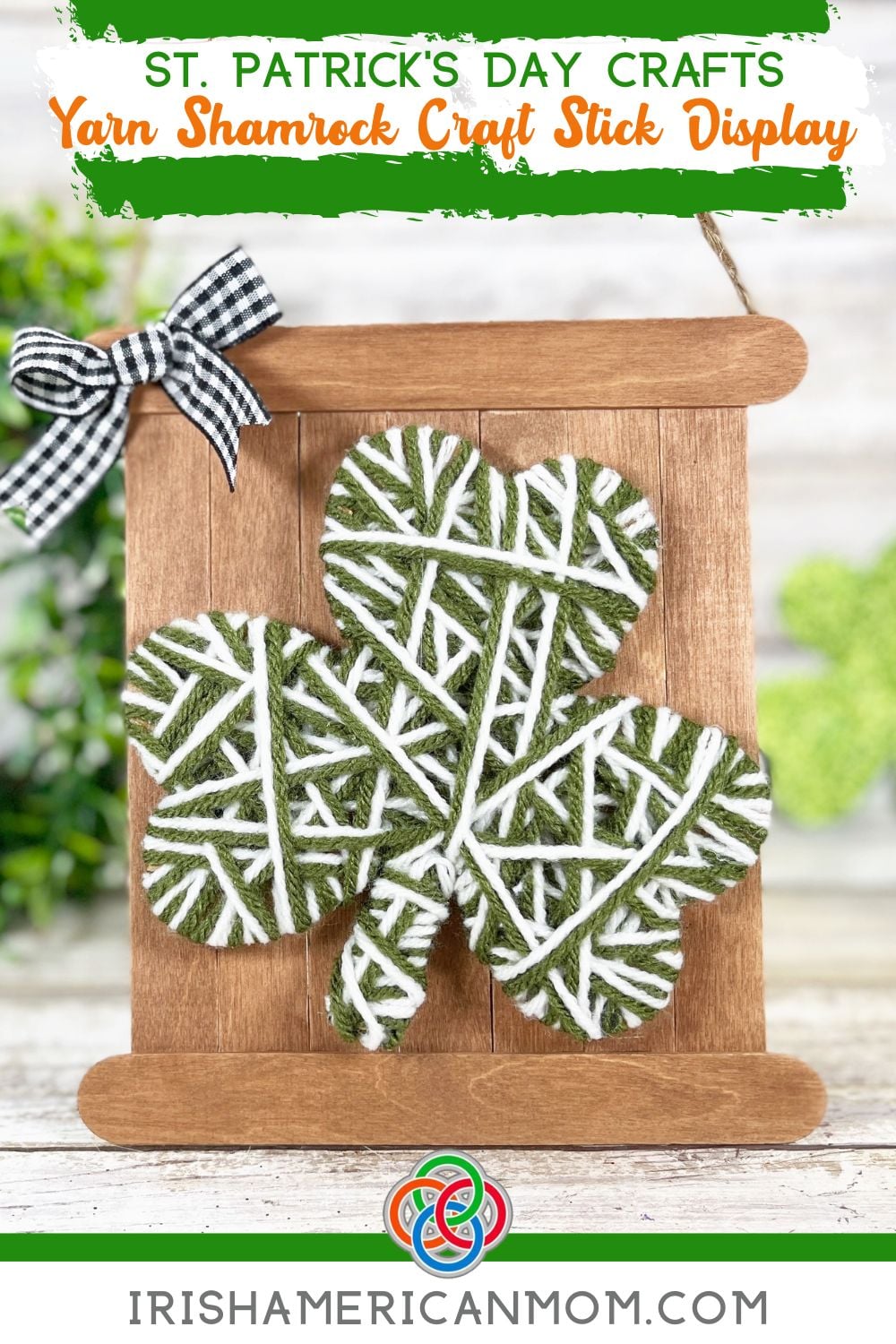 Yarn wrapped green and white shamrock mounted on a rustic craft stick sign with a gingham ribbon bow for a St. Patrick’s Day craft display.