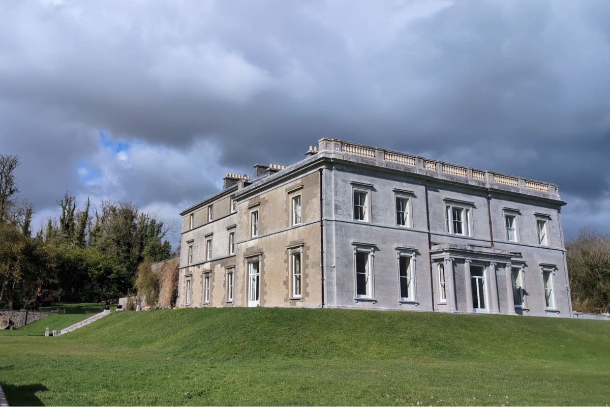 Temple House In County Sligo Ireland | Irish American Mom Temple House, a historic Georgian manor house in County Sligo, Ireland, set on a grassy hill beneath dramatic clouds in the Irish countryside.