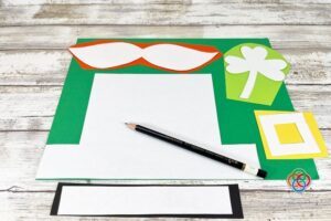 Printable template pieces for leprechaun hat, mustache, shamrock, and buckle traced onto colored cardstock with pencil during a paper plate leprechaun craft tutorial.