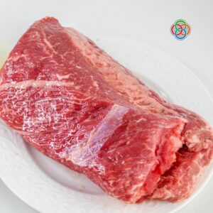 Raw uncooked corned beef brisket on a white plate ready to be seasoned and cooked in an air fryer.