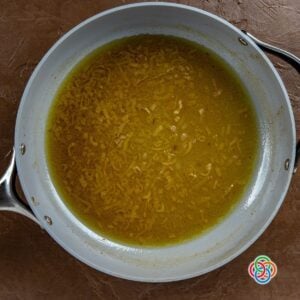 Adding beer to shallots in a skillet for a pork gravy | Irish American Mom Shallots simmering in beer in a skillet, creating a rich base for Irish-style pork gravy.