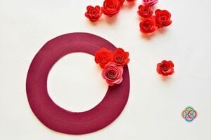 Decorative craft: a maroon circular ring with red paper roses on a light background.