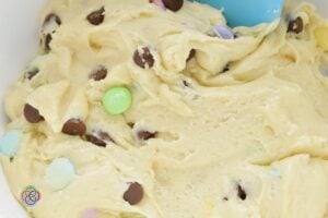 Soft cake mix cookie dough with chocolate chips and pastel M&M candies mixed in, ready to be shaped and baked.