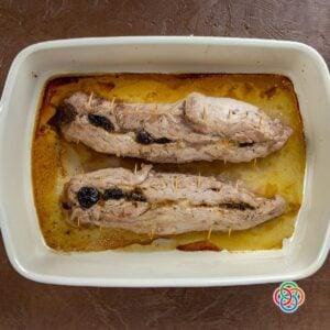 Cooked stuffed pork tenderoins with prunes | Irish American Mom Cooked pork tenderloins stuffed with prunes in a roasting dish with juices, ready to be served.