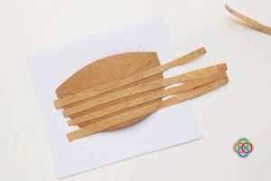 Brown cardstock basket base with paper strips placed across it to begin a woven pattern for a paper Easter basket craft.