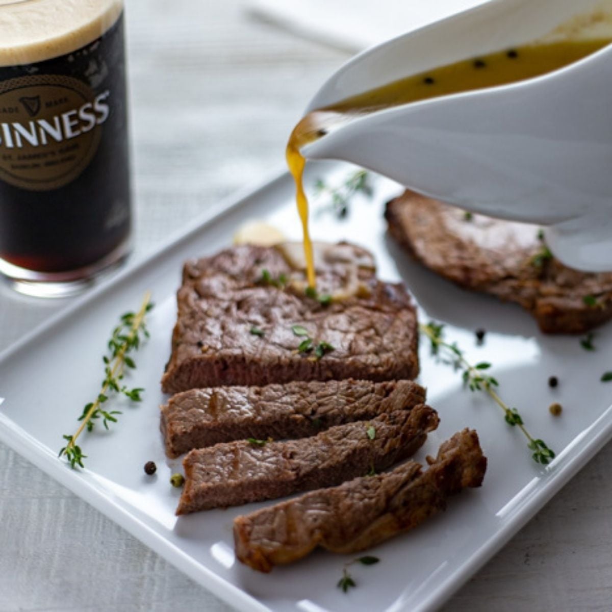 Juicy grilled steaks marinated in Guinness with a rich caramelized finished with Guinness gravy being poured over them.