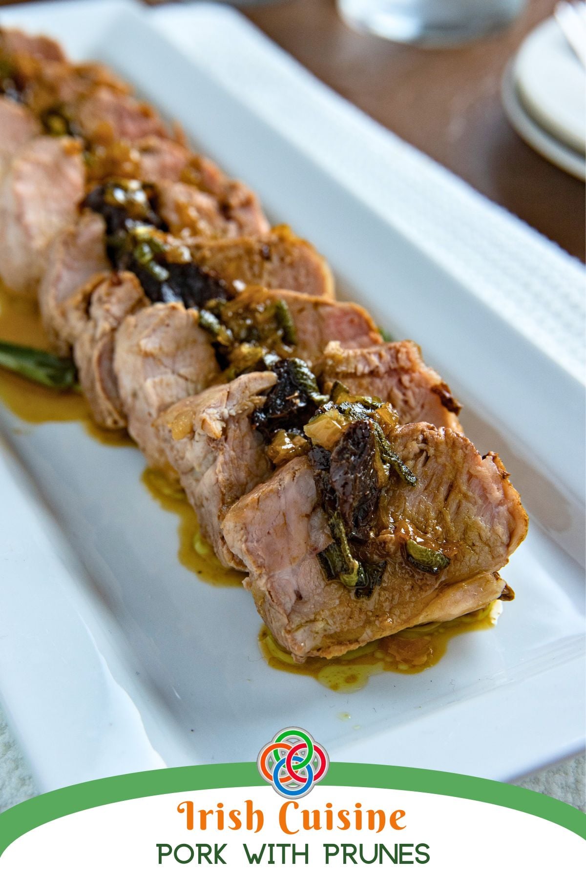 Sliced pork tenderloin with prune stuffing and savory gravy served on a white platter, labeled Irish cuisine pork with prunes.