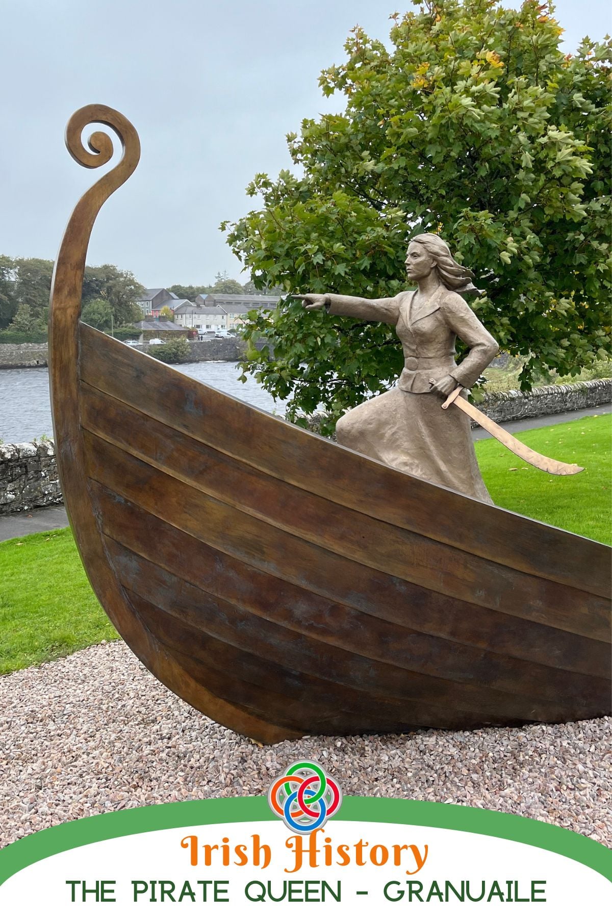 Statue of Grace O’Malley, Ireland’s Pirate Queen Granuaile, standing in a boat and pointing forward by a riverside in Ireland.