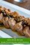 Sliced pork tenderloin with prune stuffing and savory gravy served on a white platter over a green text banner.