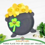 Completed paper plate pot of gold craft with yellow paper coins and gold pom poms, decorated with a green shamrock and twine bow, displayed with gold coins and greenery on a white background.