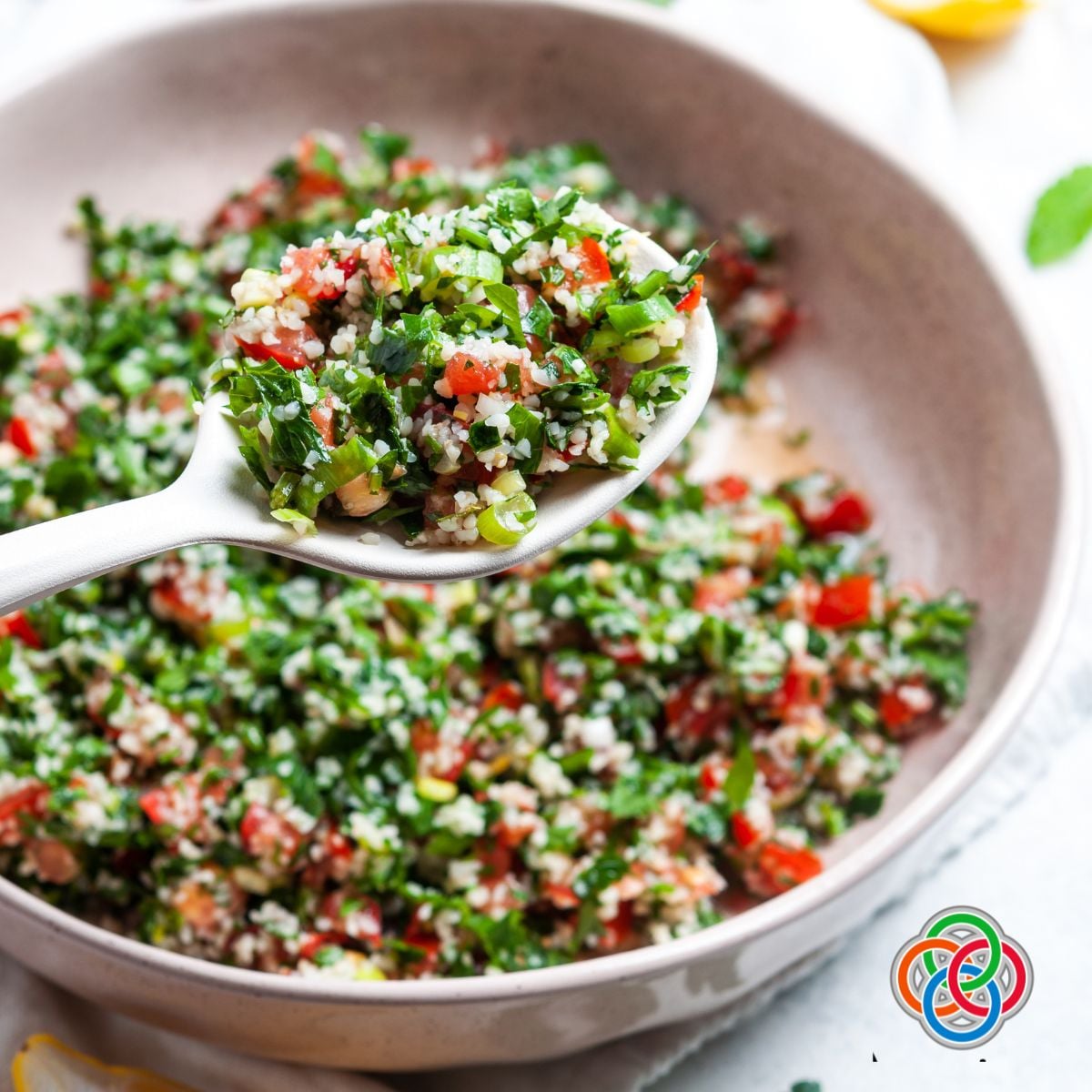 Spoonful of tabbouleh salad with bulgur wheat, parsley, and tomatoes over a bowl of tabbouleh.