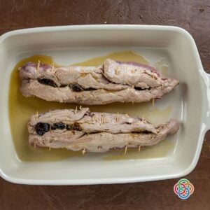 Stuffed pork steaks or tenderloins in a casserole for roasting | Irish American Mom Stuffed pork tenderloins secured with toothpicks in a casserole dish, ready for roasting with prune filling inside.
