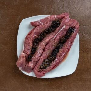 Stuffing pork tenderloins with beer soaked prunes | Irish American Mom Raw pork tenderloins filled with beer-soaked prunes, prepared for cooking in an Irish pork recipe.