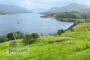 Scenic lake surrounded by green hills and mountains in the west of Ireland with Touraloora branding on the image.