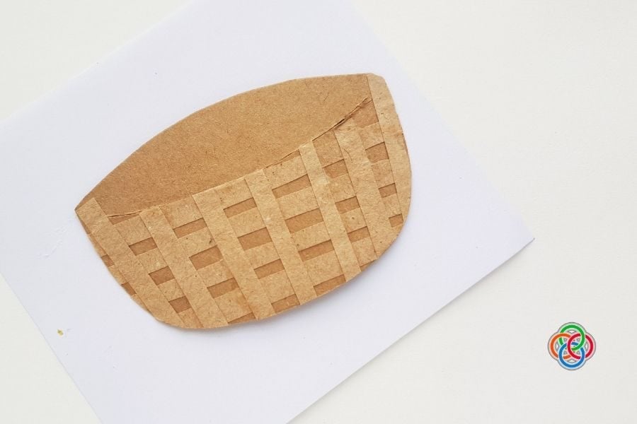 Woven paper Easter basket base made from brown cardstock with trimmed edges, placed on a white background.
