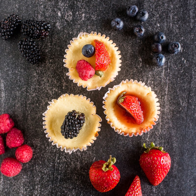 Mini cheesecakes topped with fresh fruit arranged for a brunch dessert tr