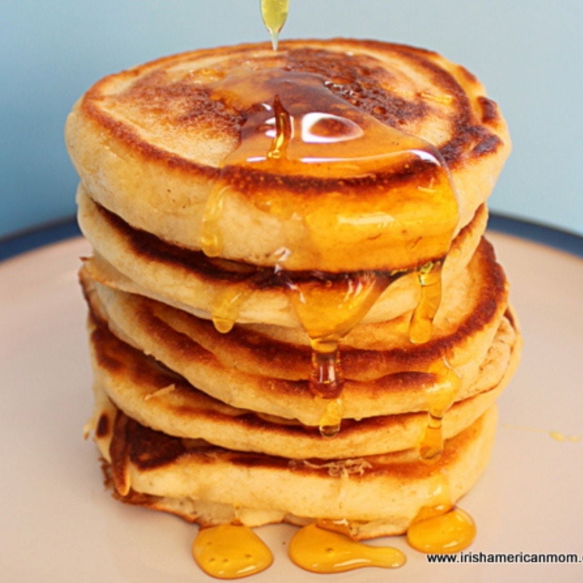 Stack of drop scones pn a plate with honey dripping over them.