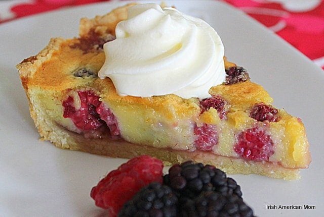 Berry Almond Tart with a swirl of cream and berries on a plate.